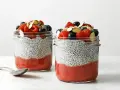 Pyszny pudding chia przepis: warstwy musu truskawkowego i nasion chia, zwieńczone świeżymi owocami i migdałami.