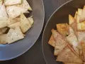 Dwa talerze pełne chrupiących chipsów z tortilli, jedne z ziołami, drugie z przyprawami. Idealne na przekąskę!