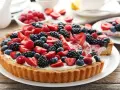 Pyszna tarta z owocami: truskawki, maliny, borówki i jeżyny na kremowym nadzieniu. Idealna na deser.
