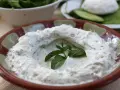 Kremowy labneh co to? Gęsty, biały serek z ziołami, udekorowany świeżą miętą, w glinianej misce.