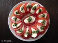 Pyszne pomidory z mozzarellą, ułożone na talerzu, posypane ziołami. Idealna przekąska na lato.