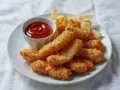 Chrupiące stripsy z kurczaka, podane z ketchupem i chipsami. Idealna przekąska na każdą okazję.