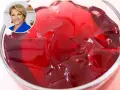 Kobieta w niebieskiej marynarce uśmiecha się obok miseczki z galaretką. Dowiedz się, ile tężeje galaretka, by cieszyć się deserem!