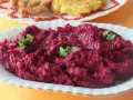 Pyszne, purpurowe buraczki na ciepło, udekorowane listkami ziół. Obok widać kotlety i placki ziemniaczane.