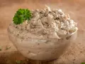 Kremowa pasta z tuńczyka, doprawiona pieprzem, w szklanej miseczce, ozdobiona gałązką natki pietruszki. Idealna na kanapki.