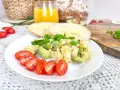 Pyszna jajecznica z awokado, podana z pomidorkami i pieczywem. Idealne śniadanie pełne zdrowych tłuszczów i białka.