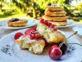 Puszyste placki na zsiadłym mleku, posypane cukrem pudrem, ozdobione czerwonymi porzeczkami i wiśniami. Idealne na letnie popołudnie.