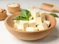Kostki tofu w drewnianej misce z bazylią. Czy tofu można jeść na surowo? Tak, to idealny składnik do sałatek i przekąsek.