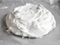 Puszysta beza pavlova na papierze do pieczenia, gotowa do wypieczenia.
