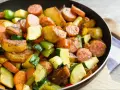 Pyszne warzywa na patelnie: ziemniaki, cukinia, marchewka i papryka, podsmażone z kiełbaską.