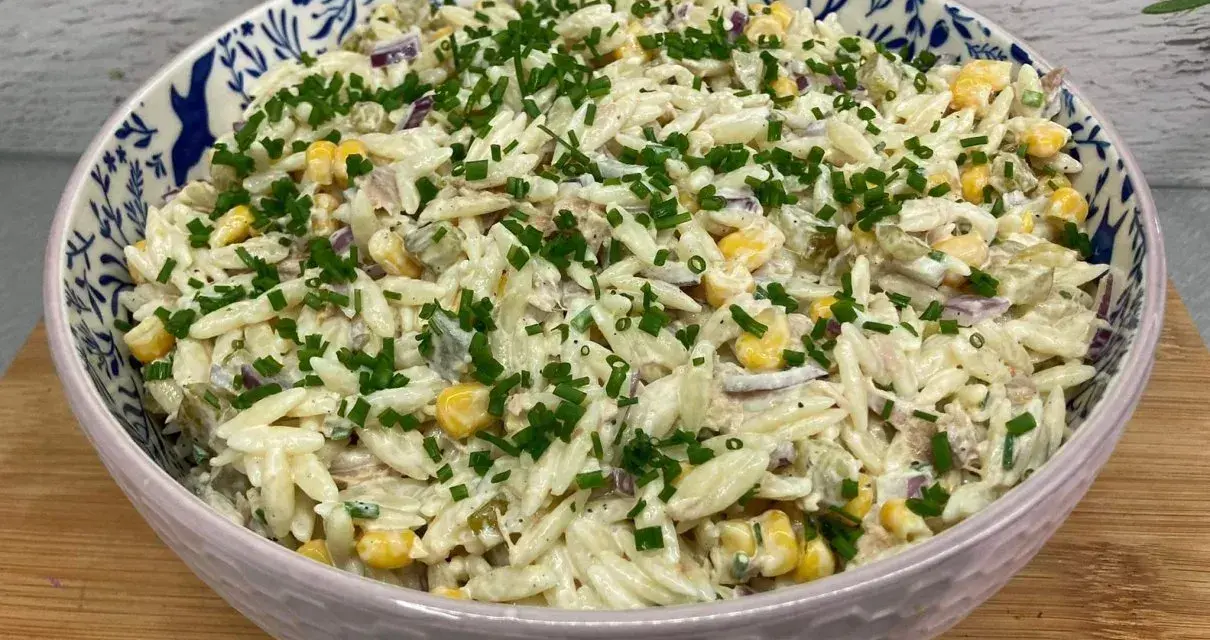 Pyszna sałatka z tuńczykiem i makaronem orzo, z kukurydzą i szczypiorkiem, w ozdobnej misce.