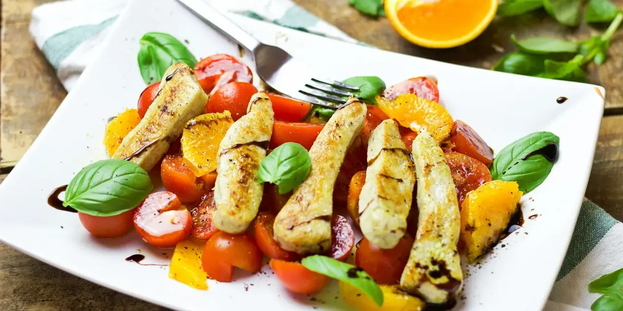 Pyszna sałatka z pomarańczą, grillowanym kurczakiem, pomidorkami i bazylią, polana sosem balsamicznym.