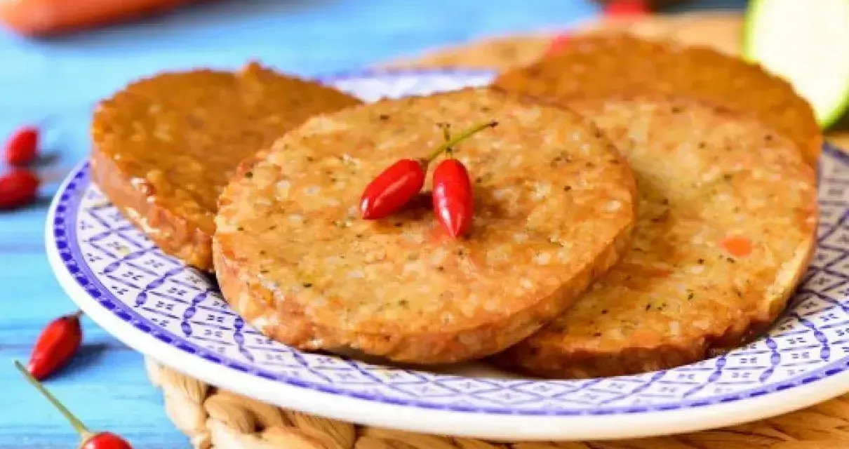 Plasterki seitanu, smażone na złoto, ozdobione dwoma papryczkami chili. Idealne do wegańskich burgerów. Seitan co to? To roślinne białko!