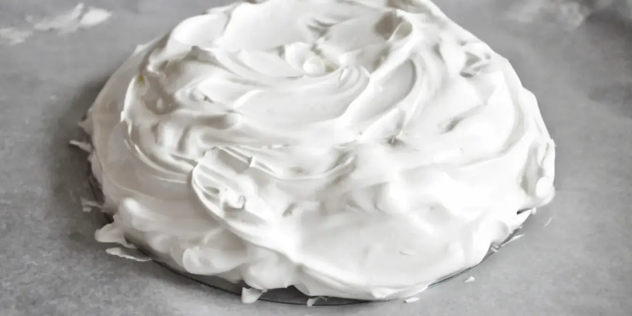 Puszysta beza pavlova na papierze do pieczenia, gotowa do wypieczenia.