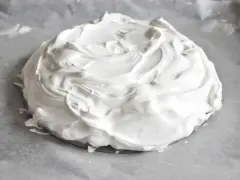 Puszysta beza pavlova na papierze do pieczenia, gotowa do wypieczenia.
