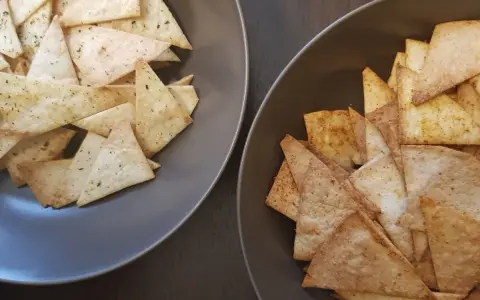 Dwa talerze pełne chrupiących chipsów z tortilli, jedne z ziołami, drugie z przyprawami. Idealne na przekąskę!