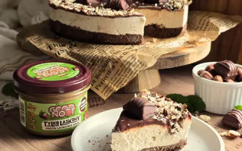 Pyszne ciasto Kinder Bueno z kremem i orzechami, obok słoiczek pasty z orzechów laskowych.