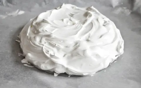 Puszysta beza pavlova na papierze do pieczenia, gotowa do wypieczenia.