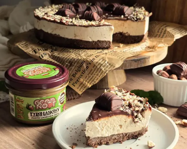 Pyszne ciasto Kinder Bueno z kremem i orzechami, obok słoiczek pasty z orzechów laskowych.