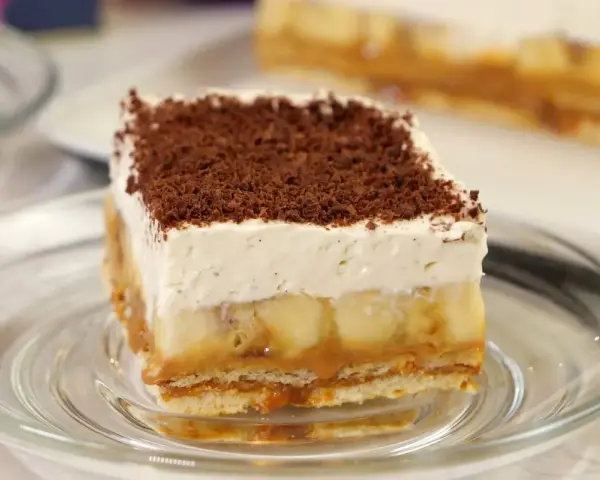 Pyszne ciasto bez pieczenia z bananami, karmelem i bitą śmietaną, posypane czekoladą. Idealne na deser.