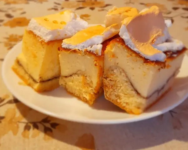 Kawałki sernika z rosą, z puszystą pianką i kruchym spodem, wyglądają apetycznie na talerzyku.