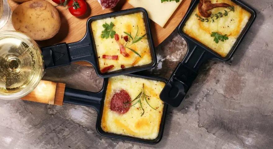 Pyszne, roztopione sery z dodatkami w patelenkach do raclette. Idealne na wspólne wieczory, gdy zastanawiasz się, co na raclette.
