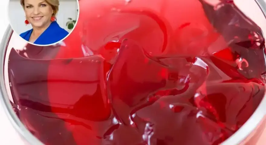 Kobieta w niebieskiej marynarce uśmiecha się obok miseczki z galaretką. Dowiedz się, ile tężeje galaretka, by cieszyć się deserem!