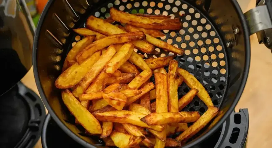 Złociste frytki w koszyku frytkownicy beztłuszczowej. Tak działa air fryer, przygotowując chrupiące przekąski.
