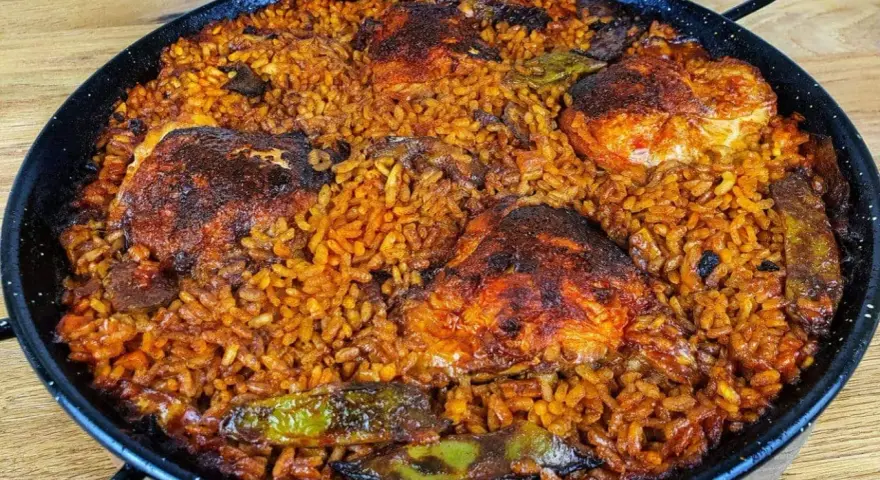Pyszna paella z kurczakiem, ryżem i warzywami w tradycyjnej patelni.