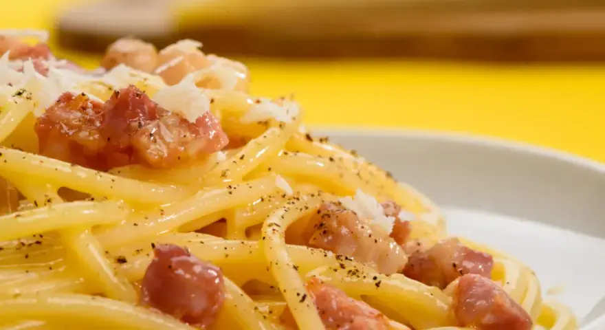 Pyszne spaghetti carbonara z kawałkami boczku i posypką. Szukasz, czym zastąpić parmezan?