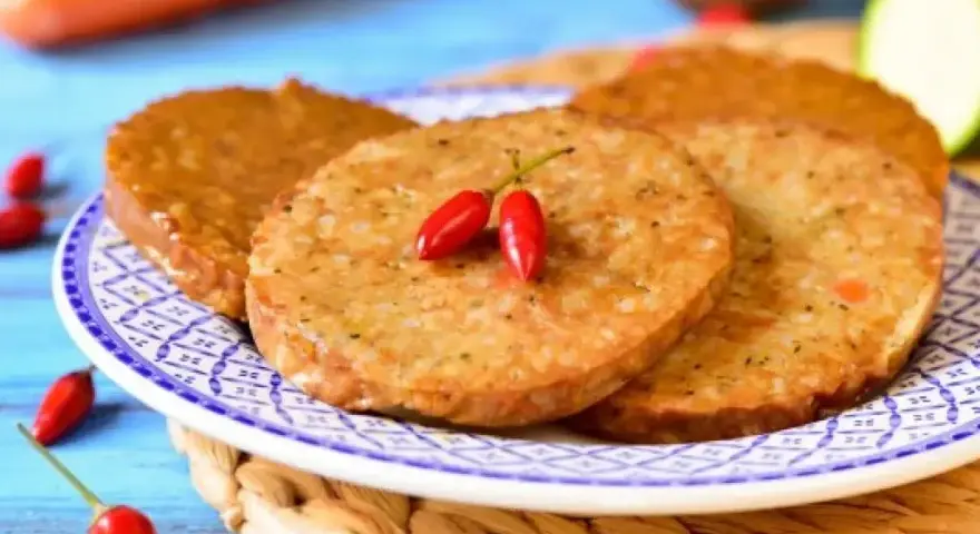 Plasterki seitanu, smażone na złoto, ozdobione dwoma papryczkami chili. Idealne do wegańskich burgerów. Seitan co to? To roślinne białko!
