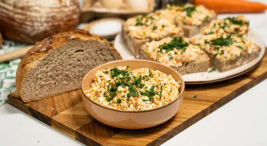 Pyszna pasta na kanapki z jajek, warzyw i ziół, podana z chlebem. Idealna na śniadanie lub przekąskę.