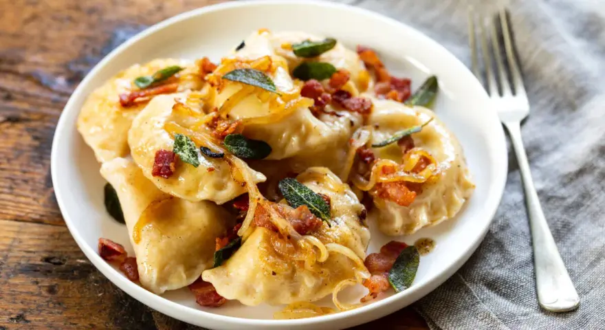 Pyszne pierogi z boczkiem i cebulką, idealne na obiad. Dowiedz się, ile gotować pierogi, by były idealne.