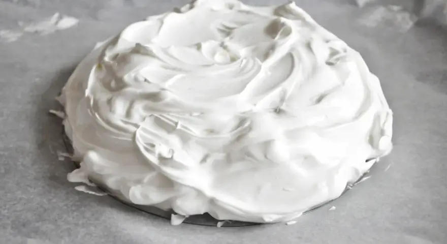 Puszysta beza pavlova na papierze do pieczenia, gotowa do wypieczenia.