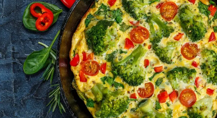 Pyszny omlet z warzywami: brokuły, pomidorki koktajlowe i papryka w złocistym jajku. Idealny na zdrowe śniadanie.