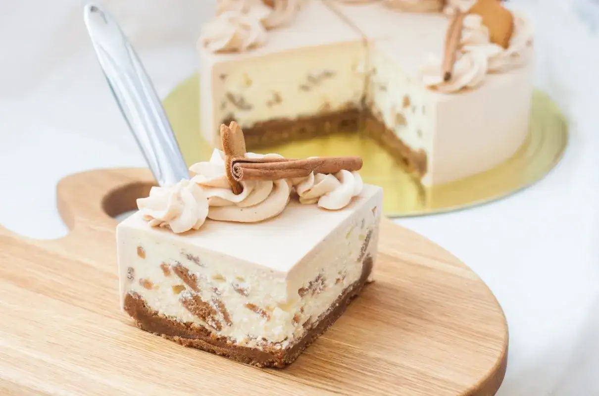 Pyszne ciasto Kinder Bueno z kremem i kawałkami ciastek, ozdobione cynamonem i bitą śmietaną.
