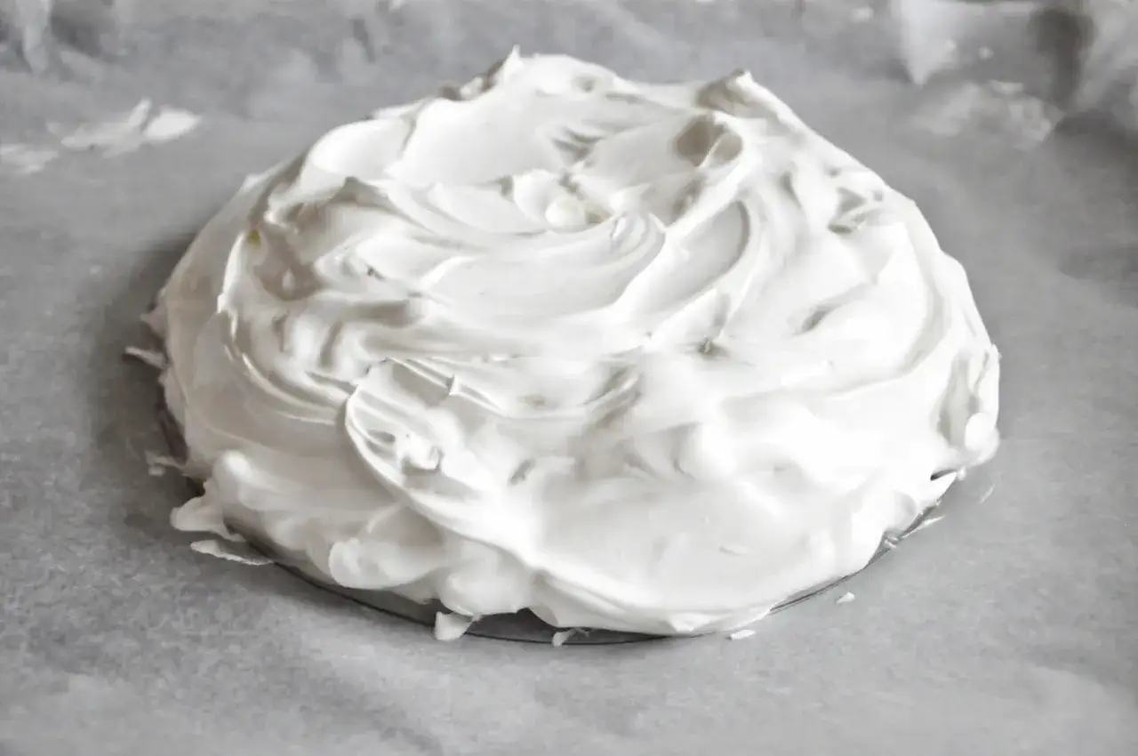 Puszysta beza pavlova na papierze do pieczenia, gotowa do wypieczenia.